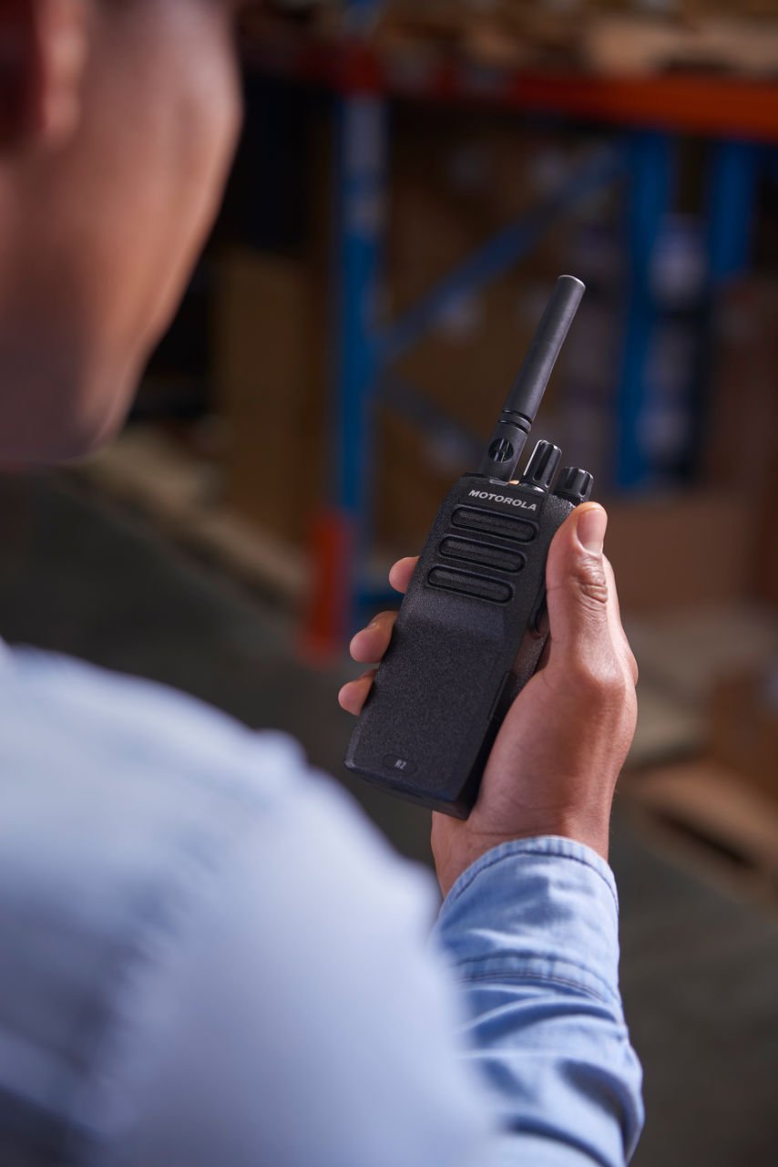 Profesional con radio Motorola R2 en operación logística, escena de referencia para alquiler de radio de comunicación