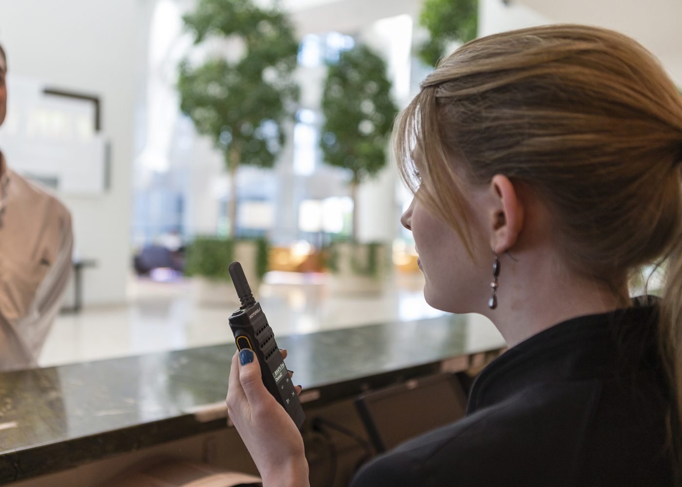 Profesional de hotelería usando radio Motorola Solutions en recepción